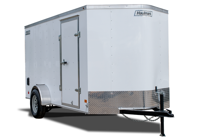 Haulmark ALX Utility enclosed trailer parked on grass under blue sky with a mountain in the …